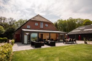 een verbouwde schuur met een patio en een huis bij B&B de Sfeerhoeve in Beilen