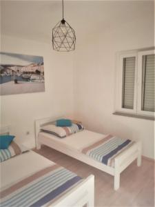 a bedroom with two beds and a pendant light at Apartments Alma in Pag