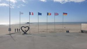 a heart statue on a beach with flags in the background at Charmant logement à 2 pas de la plage in Le Portel