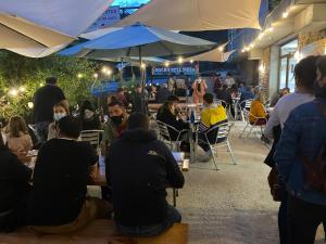 Vagabond Vieiras Beds & Dinner Albergue في La Portela de Valcarce: مجموعة من الناس يجلسون على الطاولات تحت المظلات