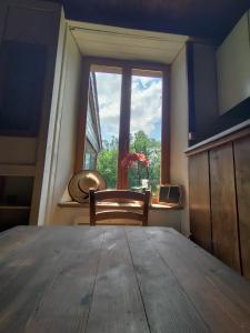 Zimmer mit einem Holztisch und einem Fenster in der Unterkunft L'Aulnerie in La Chapelle-Cécelin