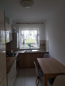 eine Küche mit einem Tisch und ein Fenster mit Vorhängen in der Unterkunft Blue apartament in Sibiu