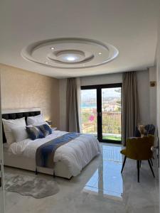 a bedroom with a large bed and a large window at Bella Address Hotel Beach in Saïdia