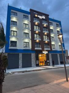 an apartment building with a light pole in front of it at Bella Address Hotel Beach in Saïdia