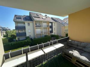 a balcony with a couch and a building at L'échappée Cabourgeaise in Cabourg