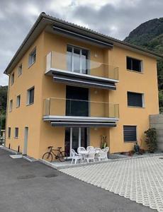 een geel gebouw met 2 tafels en een balkon bij Appartamento 3.5 Camorino-Vigana in Camorino