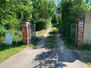 a dirt road with a gate and trees at Tornower Waldhäusl, perfekt gelegen 60 km vor Berlin, auf der Schwelle zum Spreewald und nahe Tropical Islands 