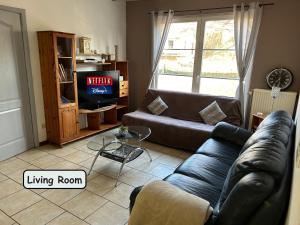 ein Wohnzimmer mit einem Sofa und ein Wohnzimmer mit einem TV in der Unterkunft L'ARIZONA Dinant - Appart Arizona, Studio Montana - Garden, Free Parking, Dog ok in Dinant