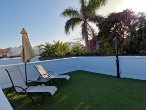 a patio with two chairs and an umbrella on a balcony at Nora Retreat (Fully Renovated) in Corralejo