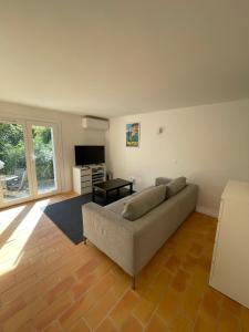 a living room with a couch and a television at Petit coin de paradis in Rayol-Canadel-sur-Mer