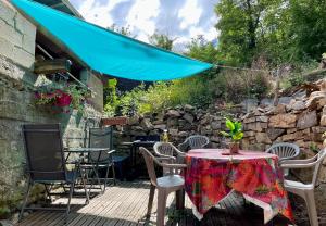 une table et des chaises sur une terrasse avec un parasol bleu dans l'établissement L'ARIZONA Dinant - Appart Arizona, Studio Montana - Garden, Free Parking, Dog ok, à Dinant