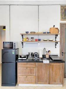 a kitchen with a black refrigerator and wooden cabinets at Le Bijou Chic in the Heart of Saigon Charm with VIEW in Ho Chi Minh City