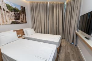 a hotel room with two beds and a tv at Titania Hotel in Sarandë