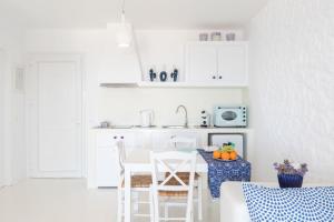 een witte keuken met een tafel en stoelen. bij Sugar Blue in Mykonos-stad