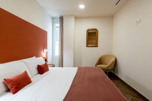 sypialnia z dużym białym łóżkiem i krzesłem w obiekcie Murillo Fantastic apartment downtown Sevilla w Sewilli