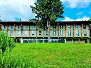 a building with a tree in front of a field at HI Geres - Pousada de Juventude do Gerês in Geres