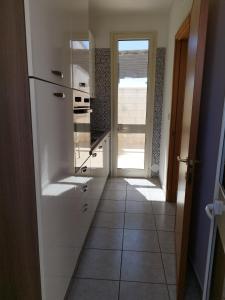 a kitchen with a white refrigerator and a tile floor at Casa vacanze Il sorriso di Emi in Torre Suda