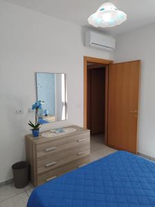 a bedroom with a blue bed and a dresser with a mirror at Casa vacanze Il sorriso di Emi in Torre Suda