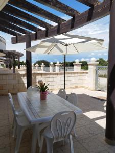 a table with chairs and an umbrella on a patio at Casa vacanze Il sorriso di Emi in Torre Suda