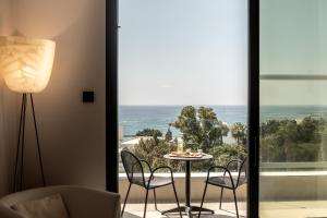 a room with a table and chairs and a view of the ocean at Anemi Hotel & Suites in Paphos