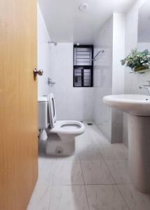 een witte badkamer met een toilet en een wastafel bij Dianella Inn in Dhaka