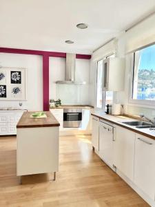 eine große Küche mit weißen Schränken und einem großen Fenster in der Unterkunft Moderno y amplio apartamento en el centro de Roses in Roses