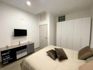 Un dormitorio blanco con una cama y un televisor de pantalla plana. en Casa Carlotta - Holiday House, en Conversano