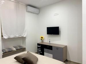 Un dormitorio con una cama y un televisor de pantalla plana. en Casa Carlotta - Holiday House, en Conversano