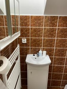 a bathroom with a white sink and brown tiles at Izba MARTINA v Penzione pod Smrekom in Martin