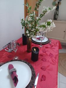 una mesa con un mantel rojo con gafas y flores en Gite avec SPA privé en Drulingen