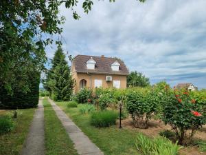 une maison avec un jardin fleuri et un trottoir dans l'établissement HutiAgi apartman, à Siófok