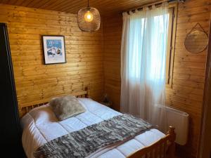 a bedroom with a bed and a window in a wooden wall at Appartement - Chalet MONT DORE COSY 6/7 personnes in Le Mont-Dore