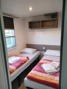 two beds in a small room with two windows at Mobil home Menanteau in Les Mathes