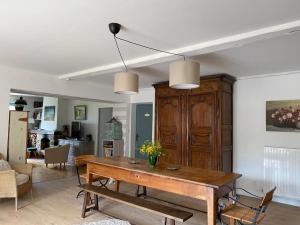 a living room with a wooden table and a kitchen at Maison sur cour in Courzieu