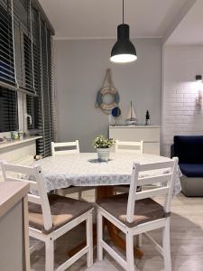 a kitchen and dining room with a white table and chairs at Apartament Ustecka Ostoja Na Wydmie in Ustka