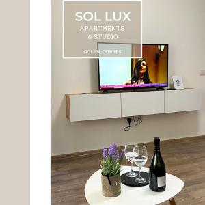 a table with wine glasses and a tv on a wall at SOL Lux Apartments 1st Floor in Durrës