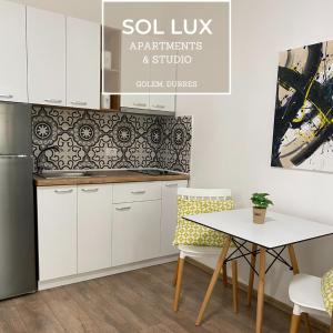 una cucina con armadi bianchi, tavolo e sedie di SOL Lux Apartments 1st Floor a Durrës