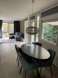 uma sala de estar com uma mesa e cadeiras verdes em Chalet Canalla em Nunspeet