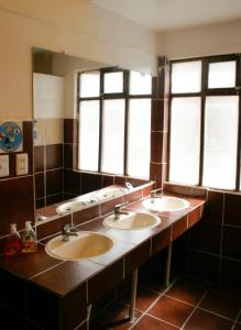 uma casa de banho com três lavatórios e duas janelas em Rummy Hostal em Uyuni