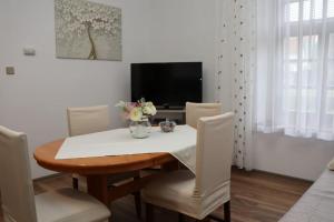 una sala da pranzo con tavolo, sedie e TV di Apartman Lagodi a Križevci