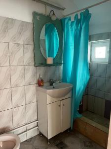 a bathroom with a sink and a blue shower curtain at Casa de vacanță Amy in 2 Mai