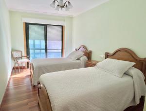 een slaapkamer met 2 bedden, een raam en een stoel bij Apartamento Bellavista in Portonovo