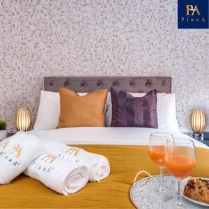a bedroom with a bed with two glasses and towels at Pluxa Sunstone Deluxe - Spacious Birmingham City Centre Stay in Birmingham