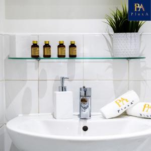 a bathroom sink with three bottles of essential oils on it at Pluxa Sunstone Deluxe - Spacious Birmingham City Centre Stay in Birmingham