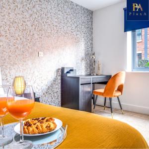 a table with a plate of food and wine glasses at Pluxa Sunstone Deluxe - Spacious Birmingham City Centre Stay in Birmingham
