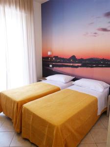 HOTEL D'ANNUNZIO في كاتوليكا: سريرين في غرفة الفندق مع لوحة على الحائط