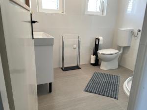 een witte badkamer met een toilet en een wastafel bij Superior Rooms Sea Side View in Rab