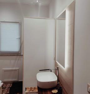 a white bathroom with a toilet and a window at Piazza Vittoria Apartment in Carini