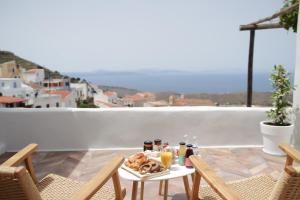 einen Tisch mit Speisen und Getränken auf dem Balkon in der Unterkunft VILLA CALLIOPE KEA in Ioulis