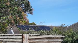 a fence with solar panels on top of a roof at Garden- Pool flat with Solar Electricity in Somerset West
